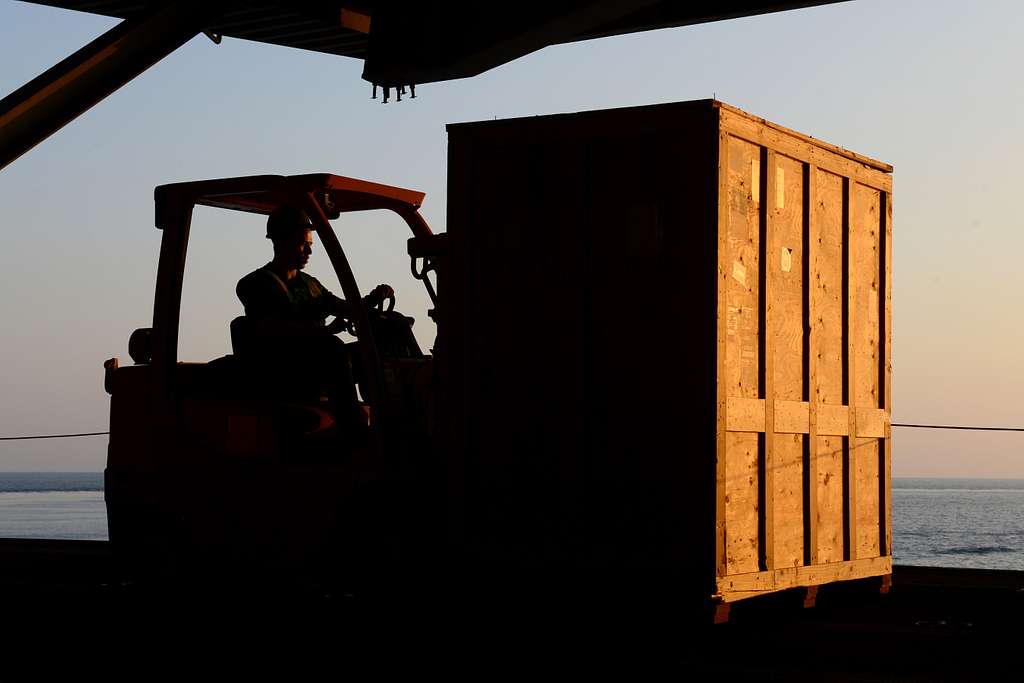 sailor moving a crate with a forklift